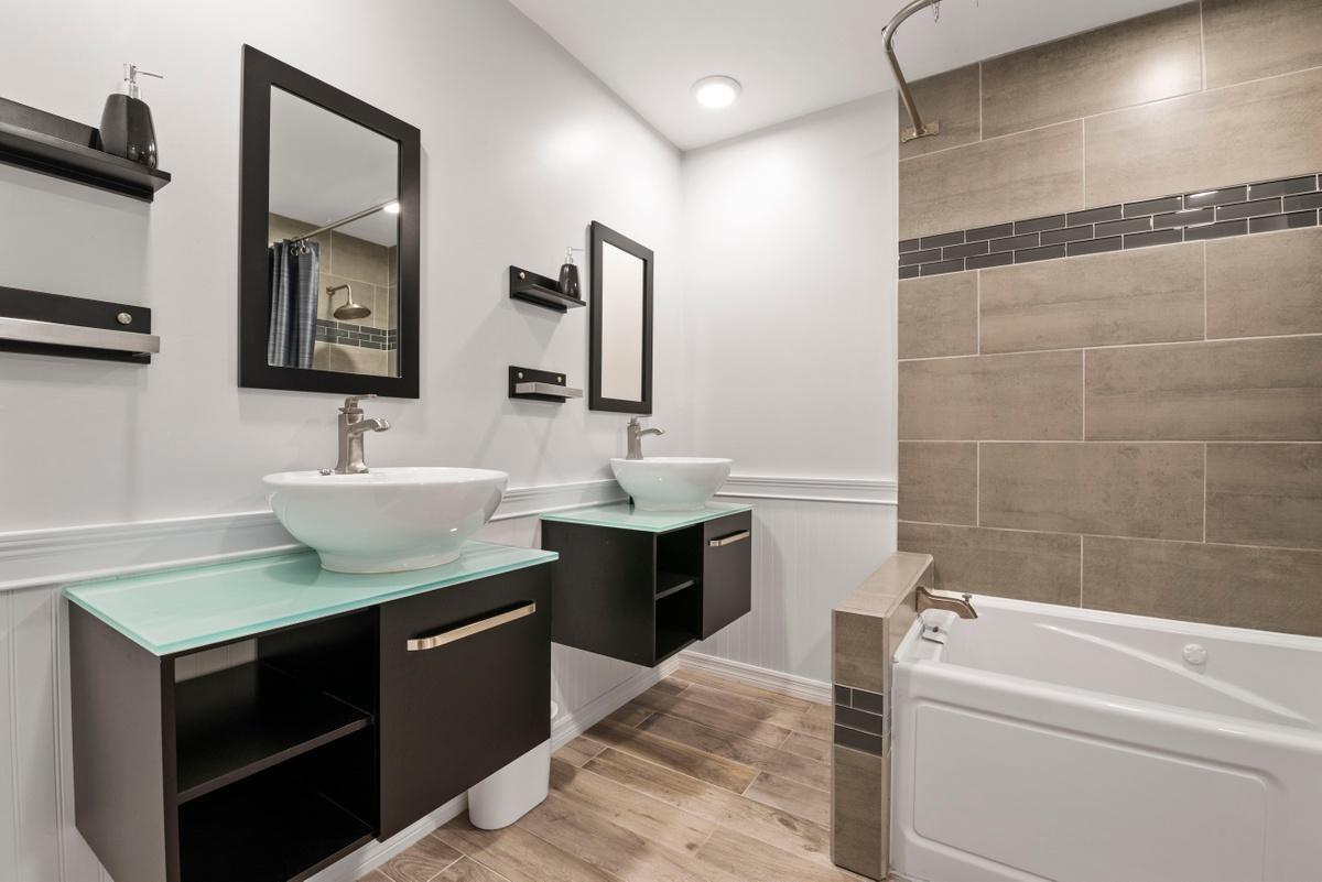 a bathroom with a tub a sink and mirror