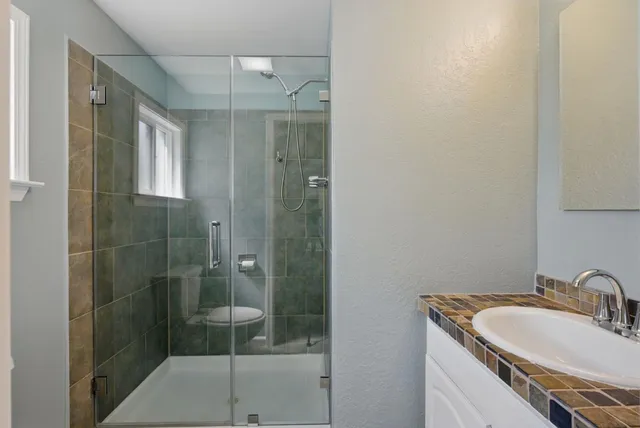 a bathroom with a shower a mirror and a sink