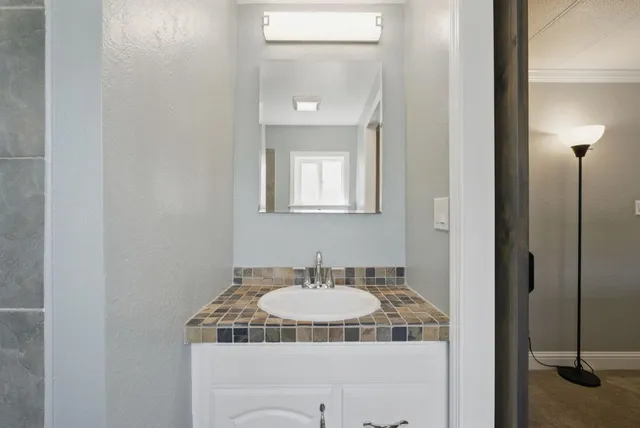 a bathroom with a granite countertop sink and a mirror