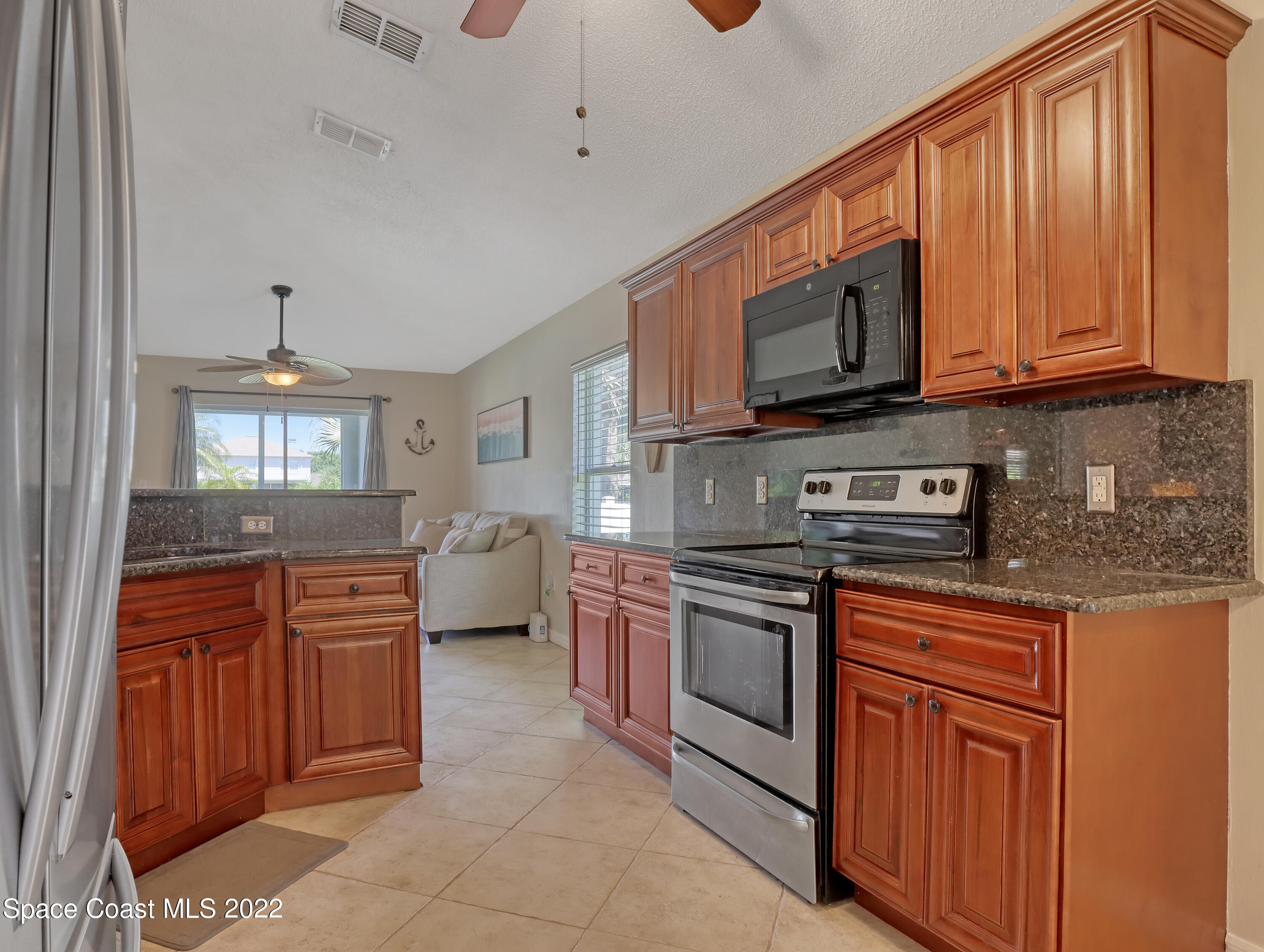 4920 Spinet Drive Melbourne, FL 32940 - Photo 9 of 44 a kitchen with stainless steel appliances granite countertop wooden cabinets a stove top oven a sink and dishwasher
