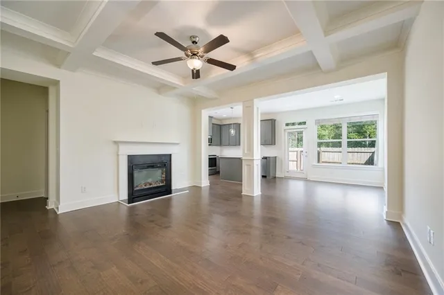 an empty room with wooden floor fireplace and windows