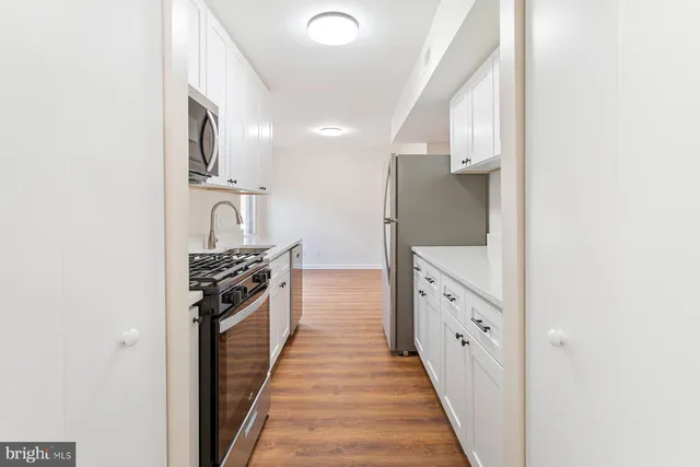 a large white kitchen with granite countertop a sink and stainless steel appliances