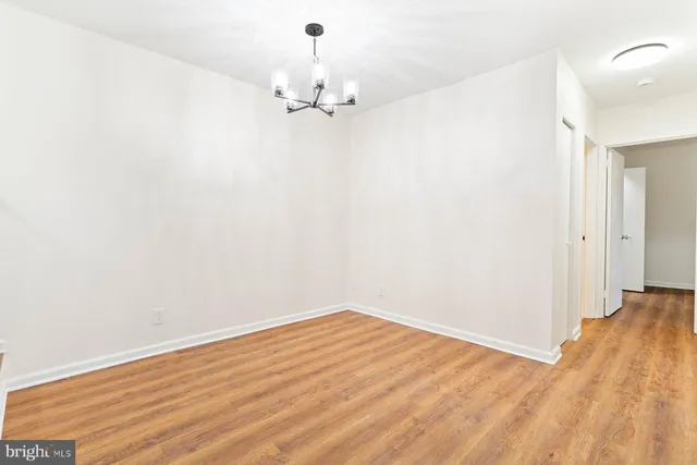 an empty room with wooden floor and chandelier fan