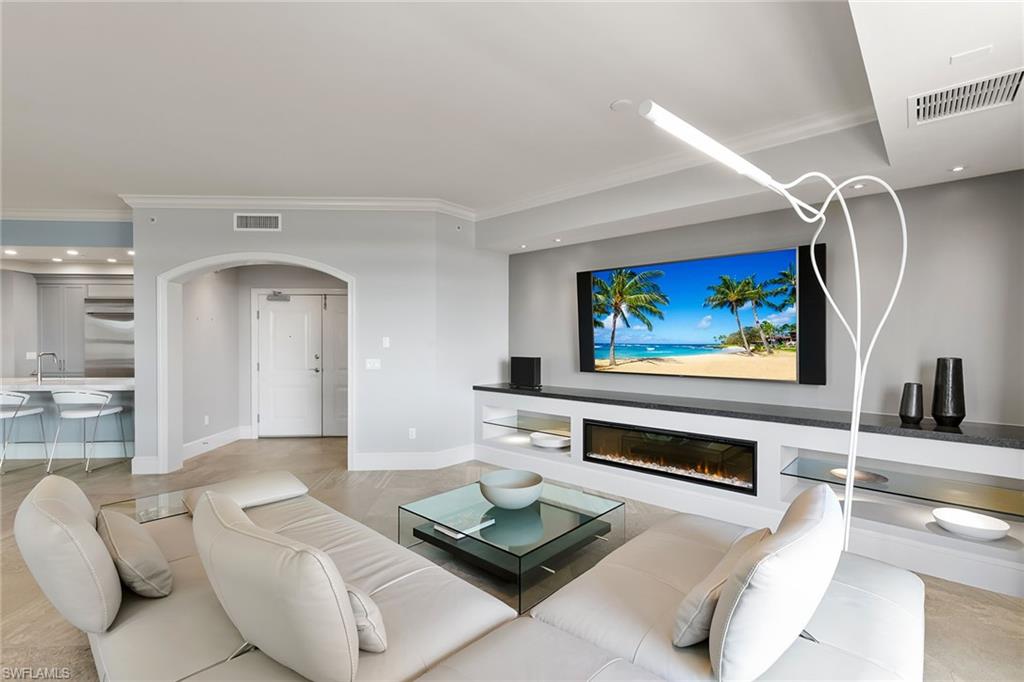 9123 Strada Place, Unit 7510 Naples, FL 34108 - Photo 35 of 38 Living room with arched walkways, a glass covered fireplace, crown molding, and recessed lighting