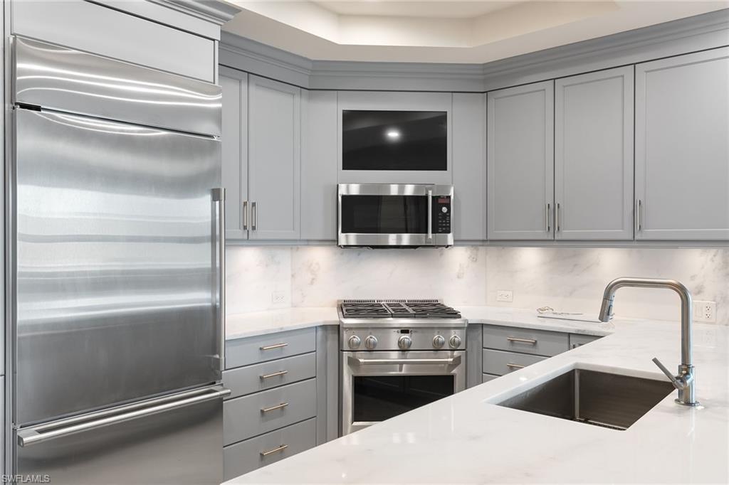 9123 Strada Place, Unit 7510 Naples, FL 34108 - Photo 10 of 38 Kitchen with high quality appliances, gray cabinetry, light stone countertops, and decorative backsplash