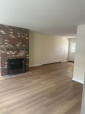 a view of an empty room with wooden floor and a fireplace