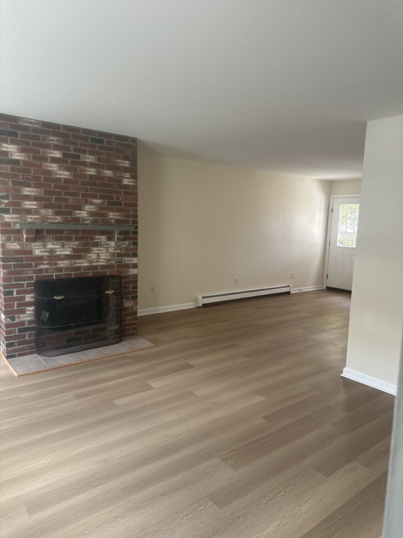 33 Denmark Street, Unit 33 Worcester, MA 01605 - Photo 4 of 10 a view of an empty room with wooden floor and a fireplace