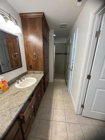 a bathroom with a granite countertop sink a mirror and shower