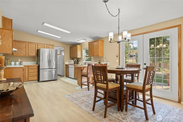 a kitchen with kitchen island a dining table chairs stainless steel appliances and cabinets