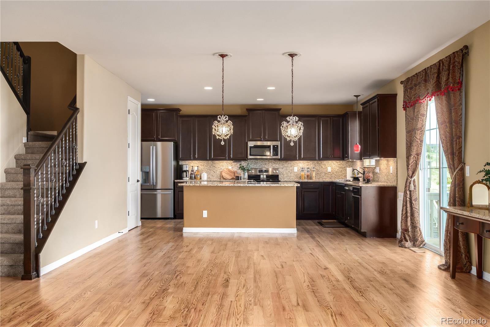 24389 East Brandt Avenue Aurora, CO 80016 - Photo 12 of 49 a kitchen with stainless steel appliances granite countertop a refrigerator a sink dishwasher a oven and a dining table with wooden floor