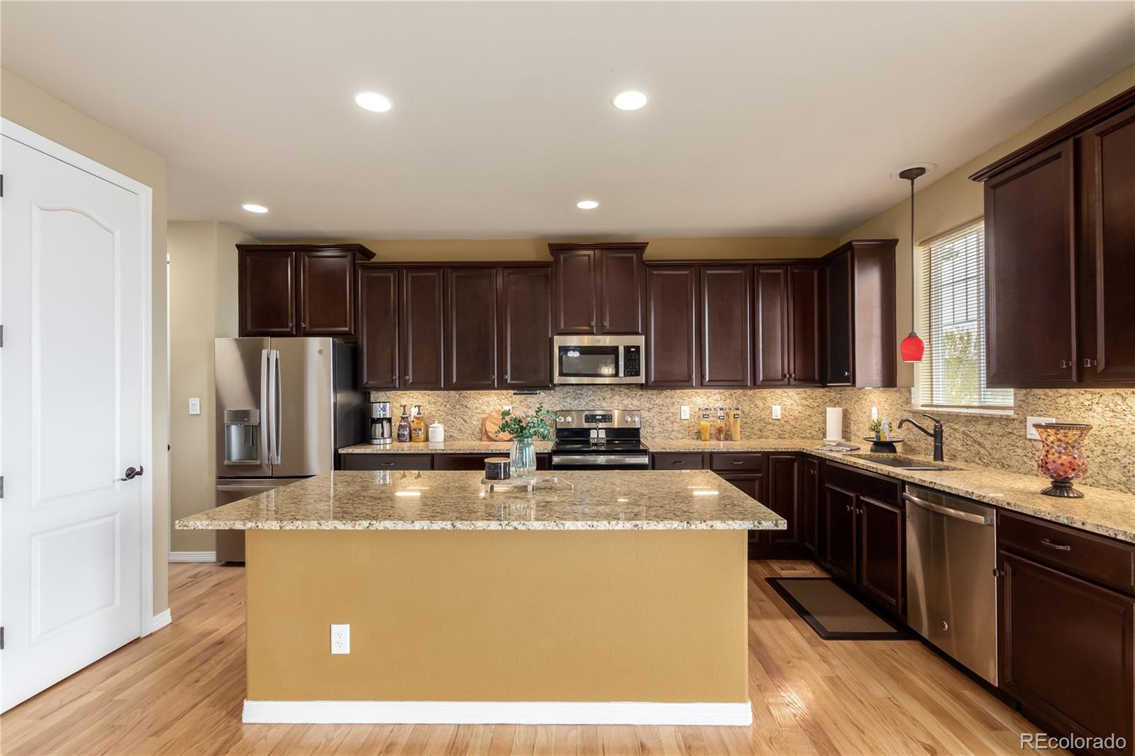 24389 East Brandt Avenue Aurora, CO 80016 - Photo 17 of 49 a kitchen with kitchen island granite countertop stainless steel appliances a sink a stove a refrigerator cabinets and a center island