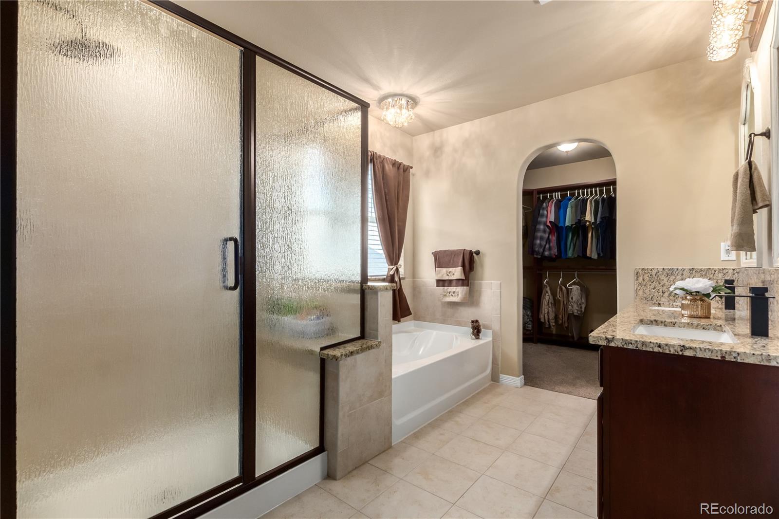24389 East Brandt Avenue Aurora, CO 80016 - Photo 21 of 49 a en suite bathroom with a double vanity sink a mirror and a bathtub