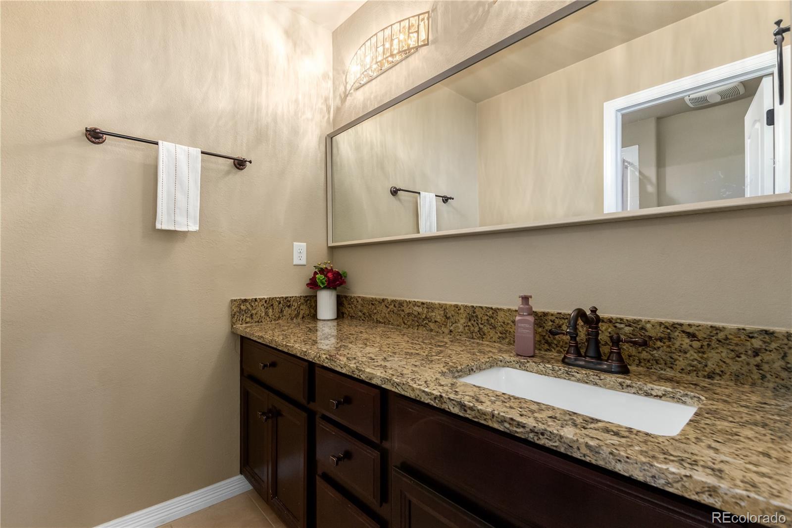 24389 East Brandt Avenue Aurora, CO 80016 - Photo 33 of 49 a bathroom with a granite countertop sink and a mirror