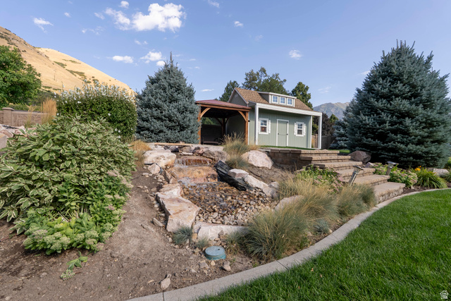 687 South 2080th Street East Springville, UT 84663 - Photo 102 of 149 Tiered landscaping featuring a rock waterfall, stone steps, and a custom storage shed with a covered patio