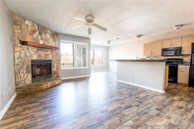an empty room with kitchen fireplace wooden floor and chandelier