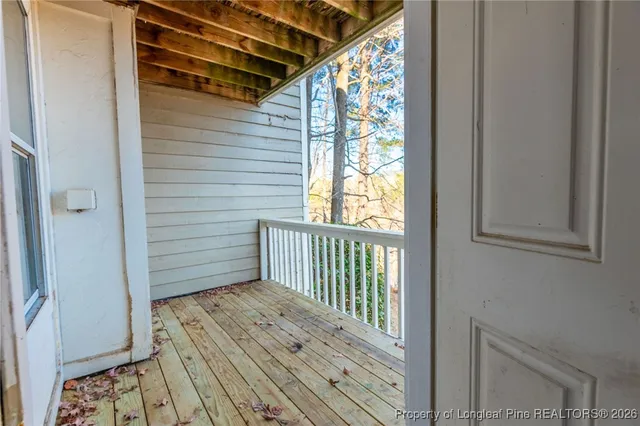 a view of a hallway with wooden floor and a bathroom