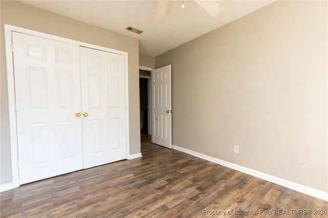an empty room with wooden floor and a ceiling fan
