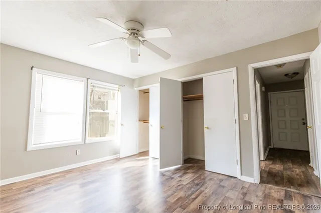a view of an empty room with wooden floor and window