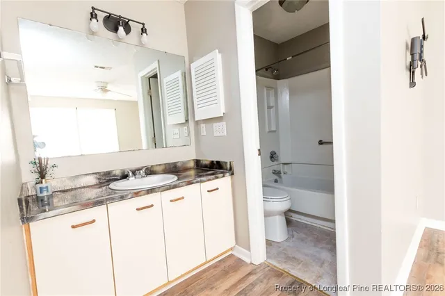 a bathroom with a granite countertop sink a toilet a mirror and shower