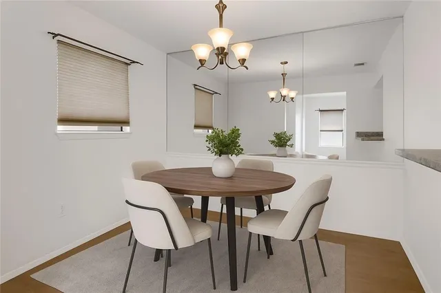a dining room with wooden floor a chandelier a wooden table and chairs