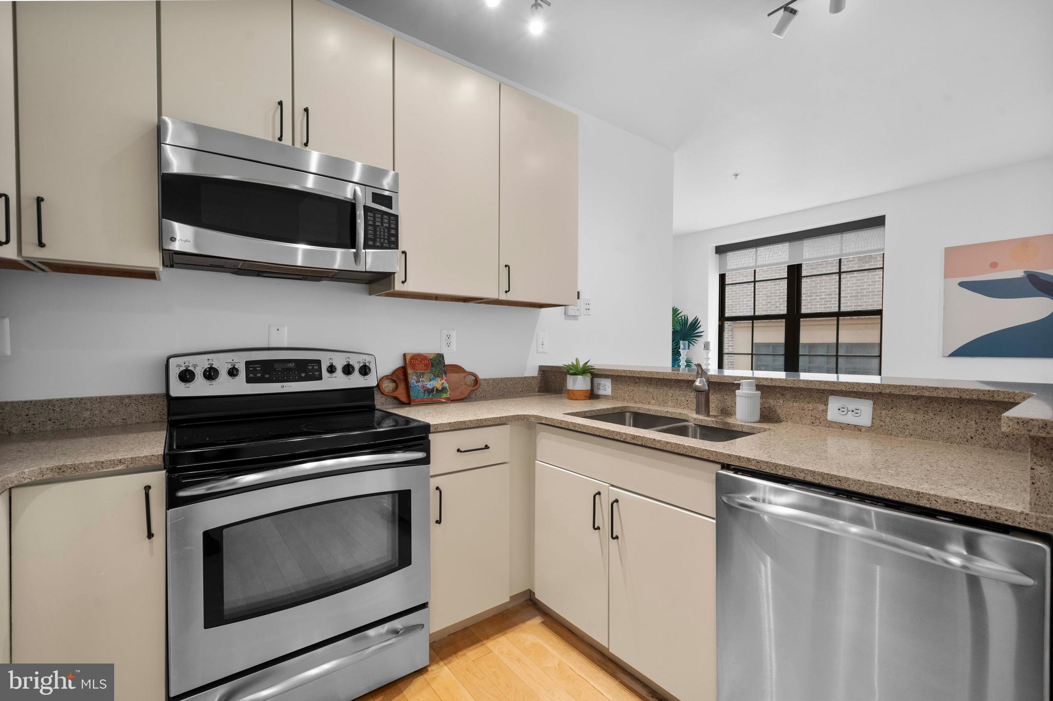 2412 17th Street Northwest, Unit 102 Washington, DC 20009 - Photo 5 of 21 a kitchen with stainless steel appliances granite countertop a sink a stove a microwave and wooden cabinets