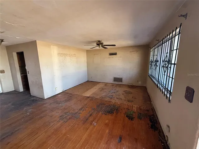 an empty room with wooden floor and windows