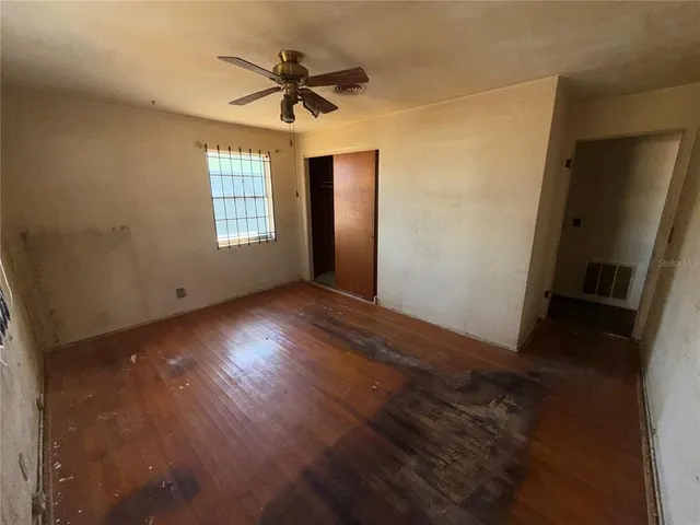 an empty room with wooden floor and windows