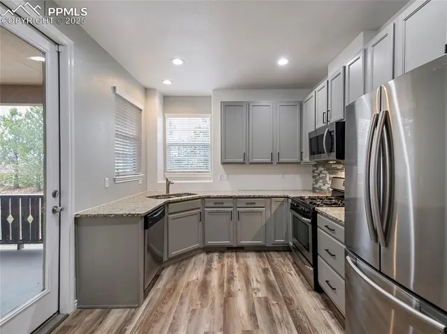 a kitchen with stainless steel appliances granite countertop refrigerator a sink dishwasher a stove and white countertops with wooden floor