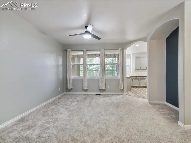 an empty room with windows and chandelier fan