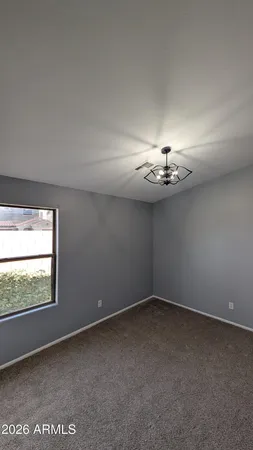 an empty room with windows and chandelier fan