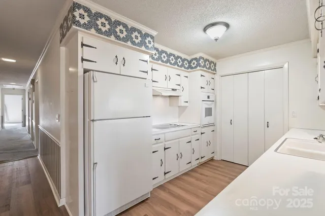 a kitchen with granite countertop a refrigerator a sink and cabinets