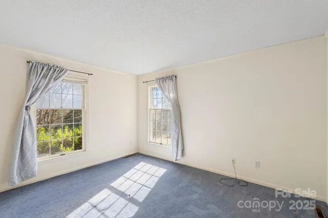 an empty room with windows and a fireplace