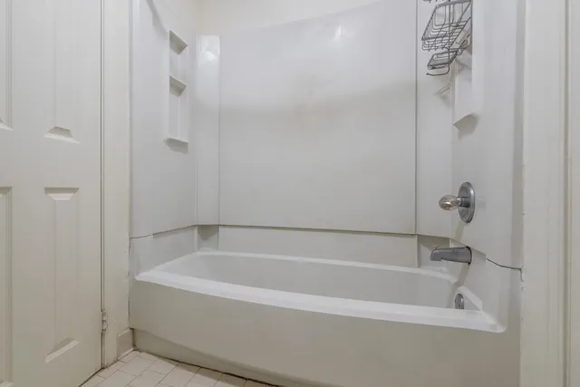 a white bath tub sitting next to a shower