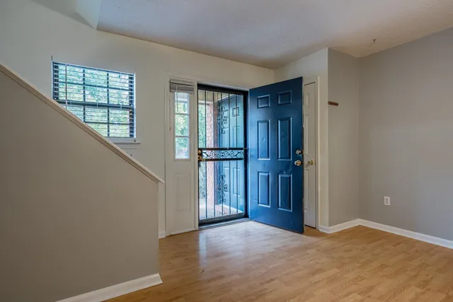 a view of an empty room with wooden floor and a window