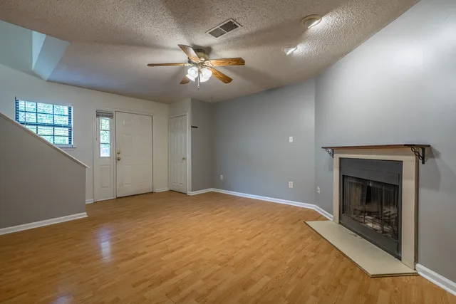 a view of an empty room with chandelier fan and wooden floor