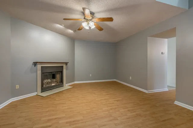 an empty room with chandelier fan and windows