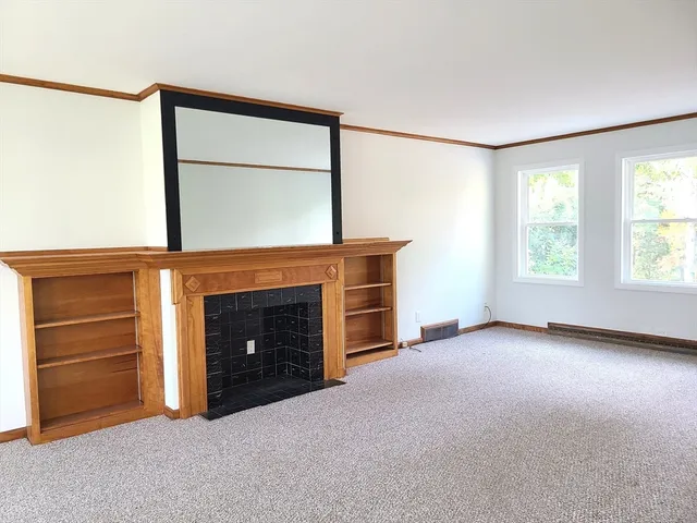 a view of an empty room with a fireplace and a window