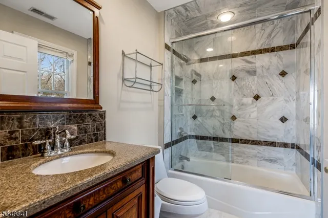 a bathroom with a granite countertop sink toilet and shower
