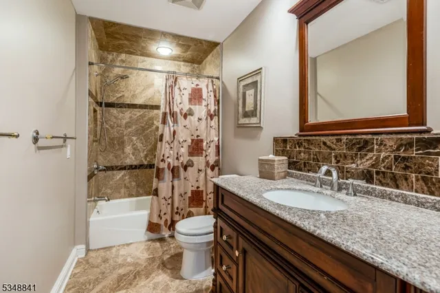 a bathroom with a granite countertop sink a mirror a bathtub and toilet