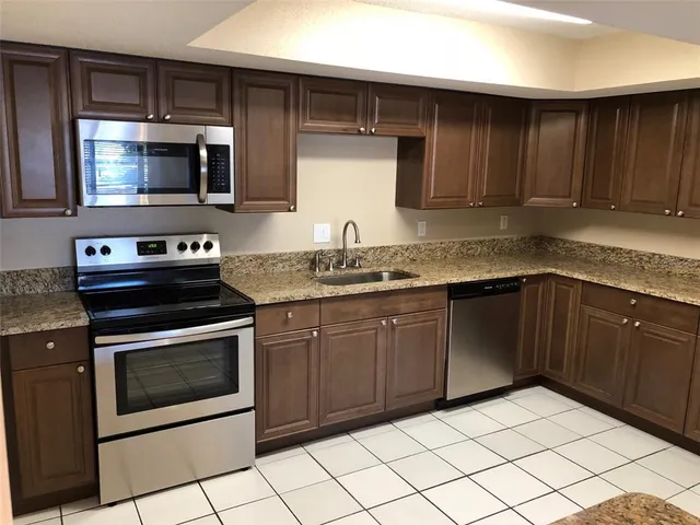 a kitchen with granite countertop a stove top oven microwave and cabinets