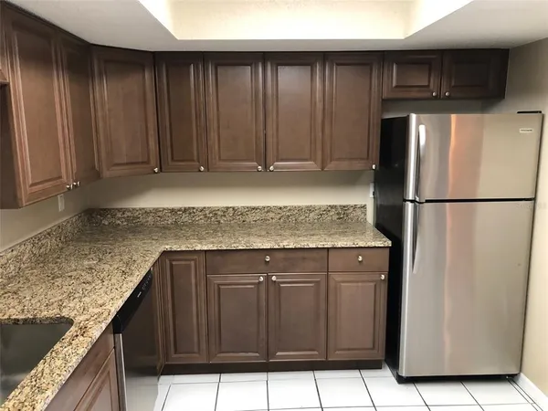 a kitchen with granite countertop a sink refrigerator and cabinets