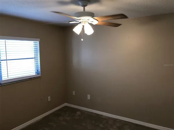 an empty room with a window and a fan