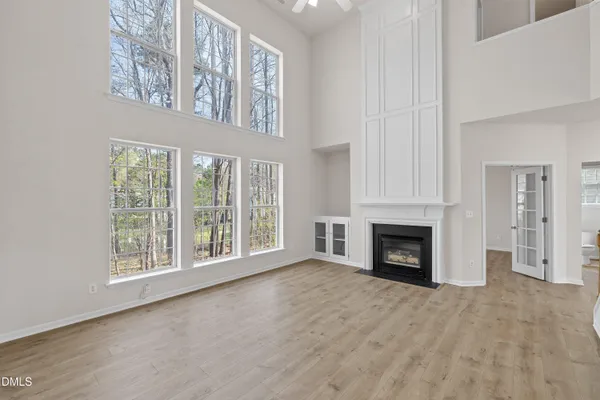 a view of an empty room with a window and kitchen view
