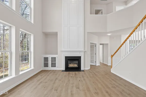a view of an empty room with wooden floor fireplace and a window