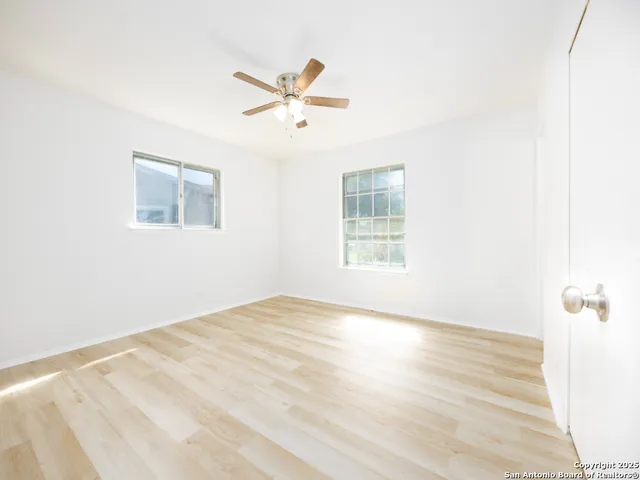 a view of empty room with wooden floor and fan
