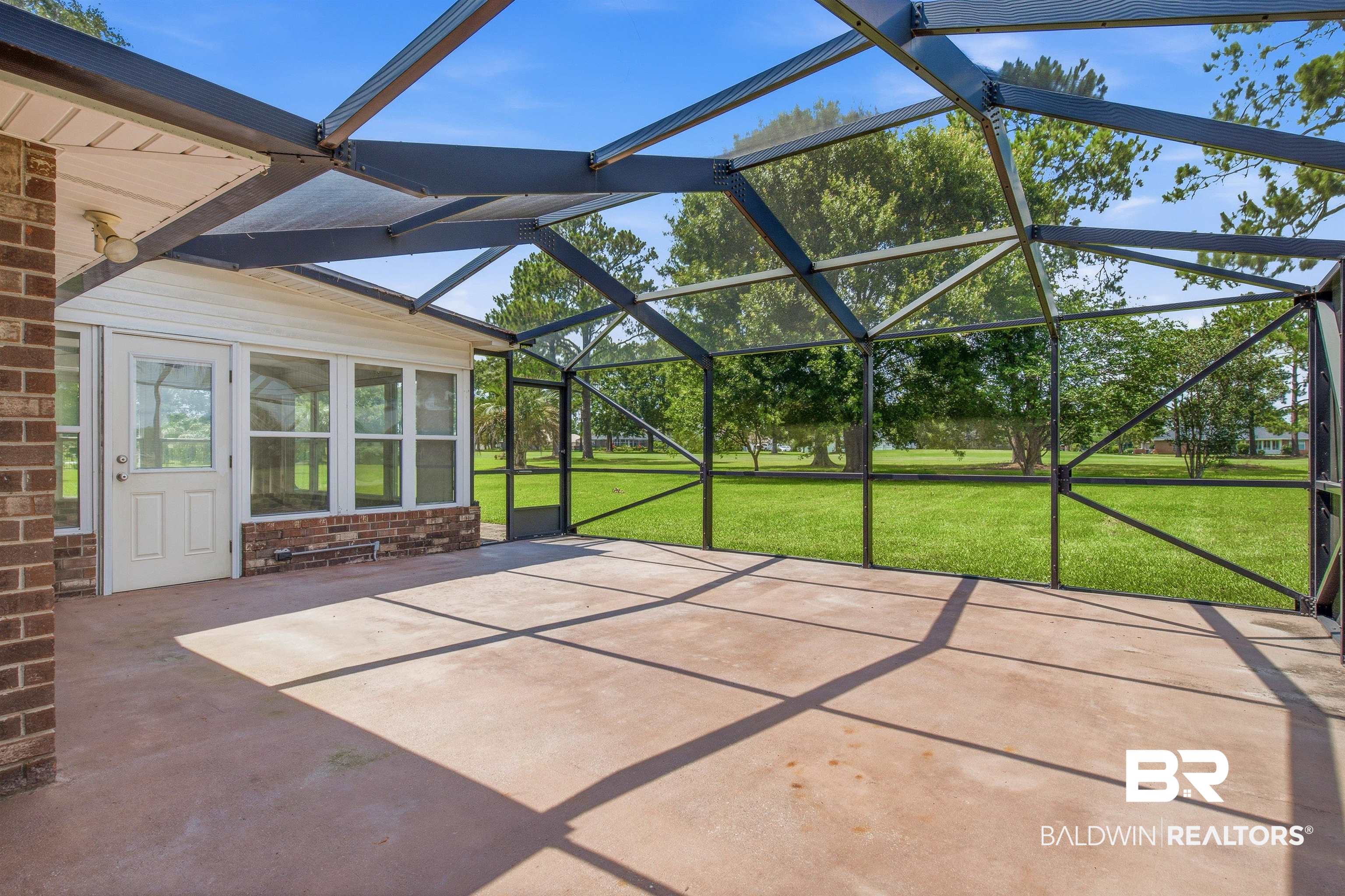 22685 County Road 12 Foley, AL 36535 - Photo 18 of 89 Expansive screened patio featuring a concrete surface, direct access to a sunroom, and surrounded by mature trees