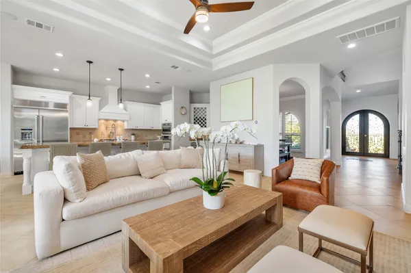 a living room with furniture kitchen view and a chandelier