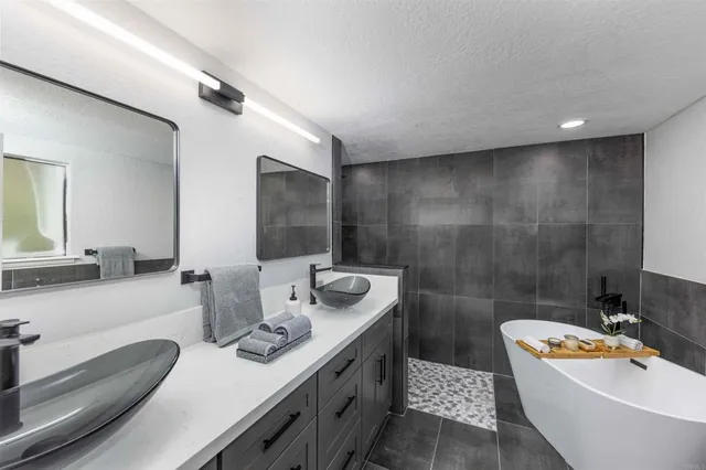 a bathroom with a granite countertop sink and a bathtub