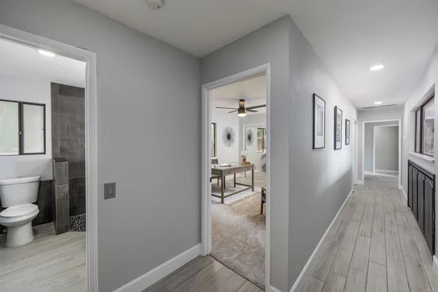 a view of a hallway with wooden floor and a living room
