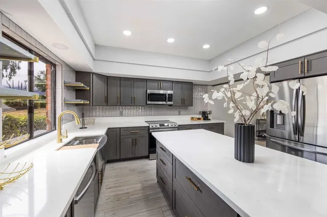 a kitchen with stainless steel appliances granite countertop a sink a stove and a refrigerator